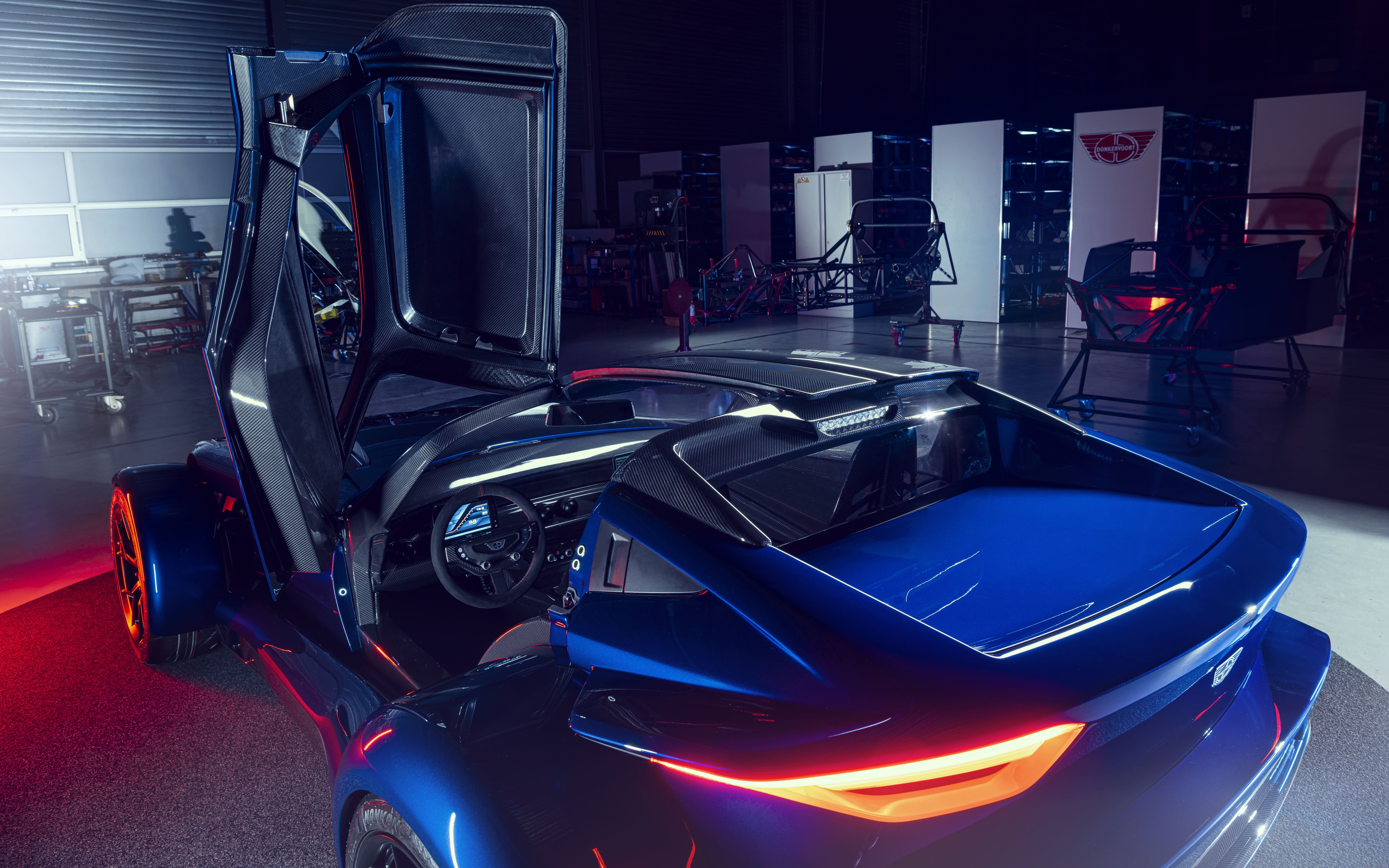 Елегантний спортивний автомобіль сріблястого кольору з металевим відтінком, на тлі темного фону відбиває м’яке світло студійних ламп.